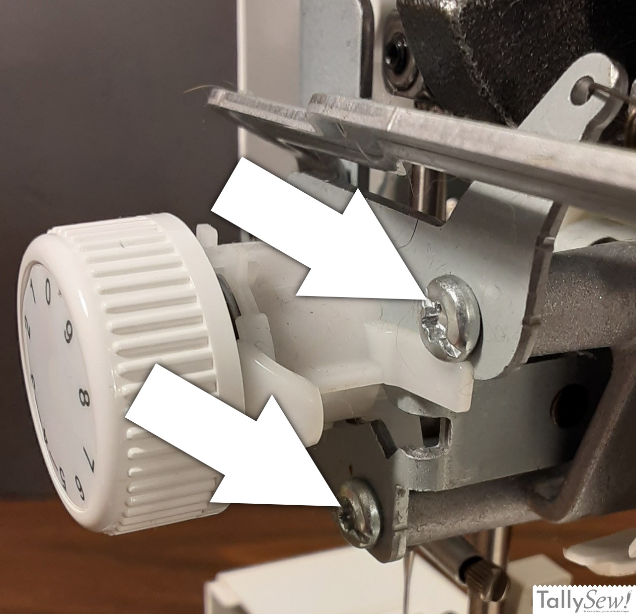 Pointing out the two screws that hold the tensioner bracket in place in a Brother JX2517 sewing machine