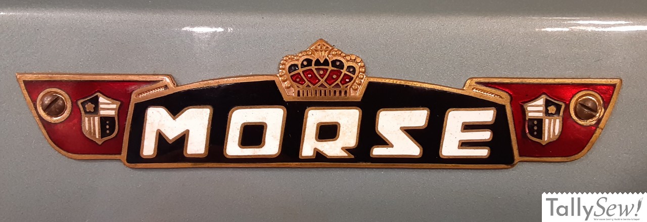 Morse 600 sewing machine main badge on the arm of the machine that says "MORSE" and is flanked with a shield on each side and there is a crown above the wording