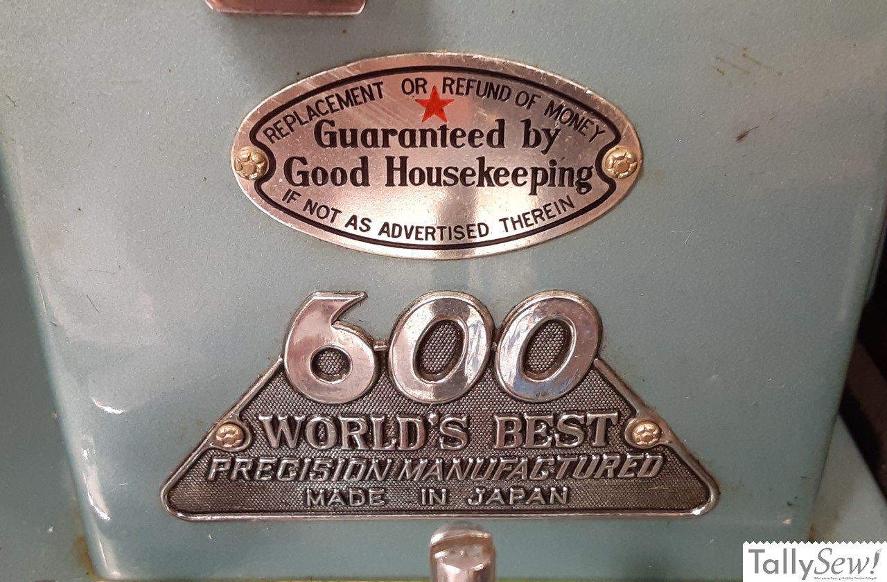 Morse 600 sewing machine Column badges. The top badge reads "REPLACEMENT OR REFUND OF MONEY IF NOT AS ACVERTISED THEREIN" and "Guaranteed by Good Housekeeping". The lower badge reads "600 WORLD'S BEST PRECISION MANUFACTURED MADE IN JAPAN"
