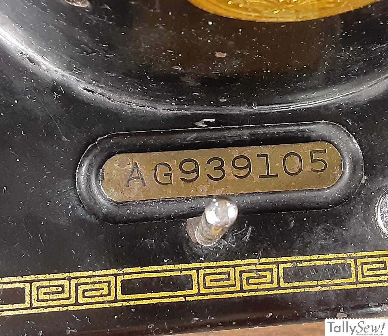A detailed close-up of the brass plaque on a Singer 201-2 sewing machine, clearly showing the stamped serial number used to date the machine.