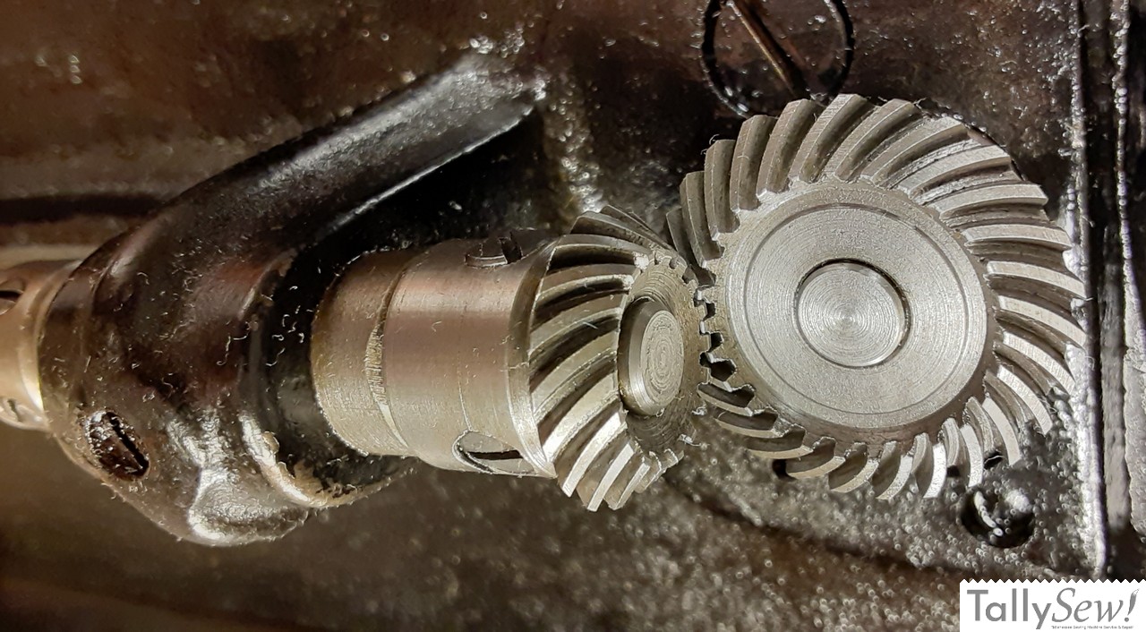A close-up of the all-metal internal gears of a Singer 201-2, showing the lower drive gear (right) connected to the vertical drive shaft.