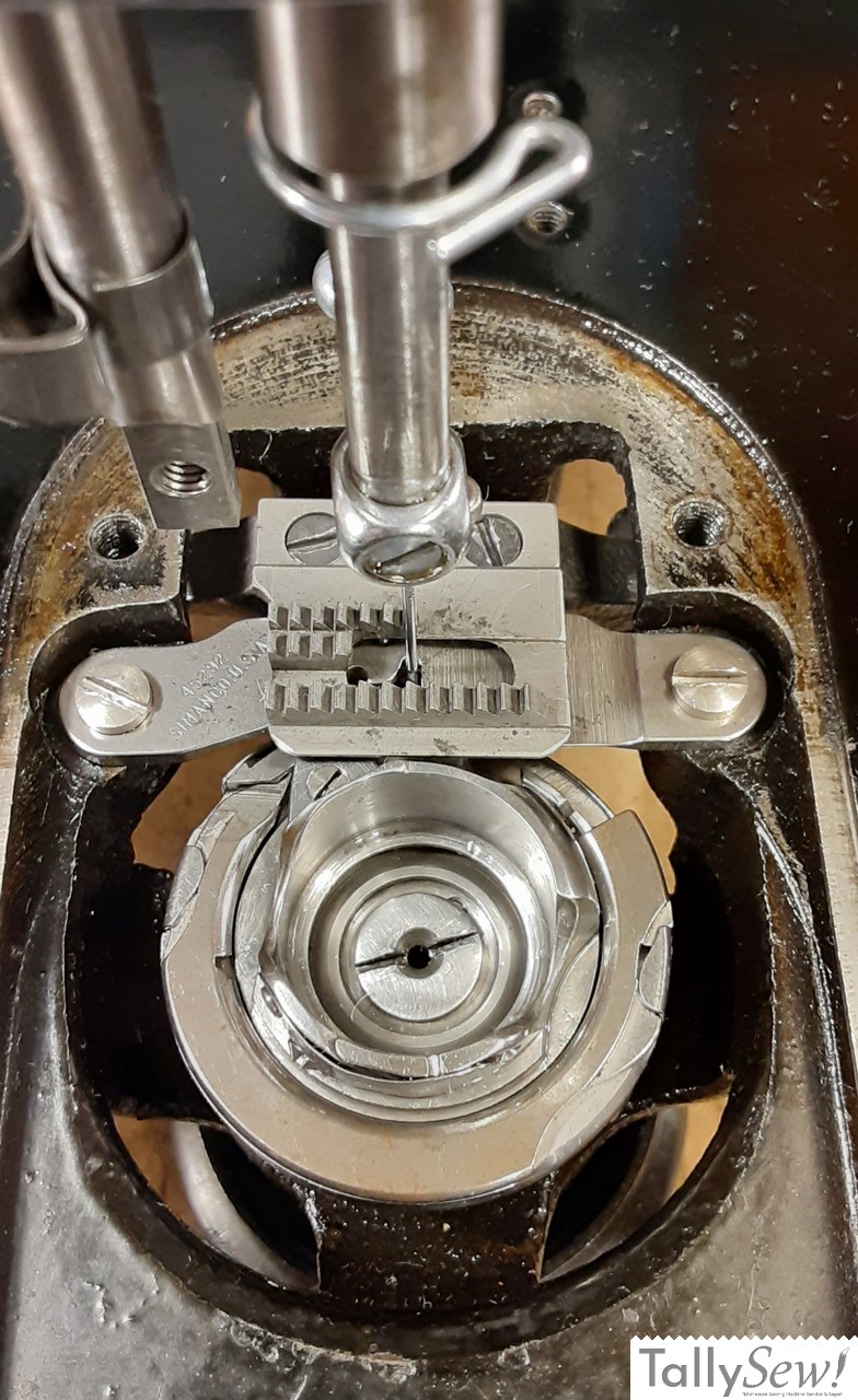 Top-down view of the bobbin area on a Singer 201-2, with the throat and slide plates removed to expose the all-metal rotary hook mechanism and feed dogs.