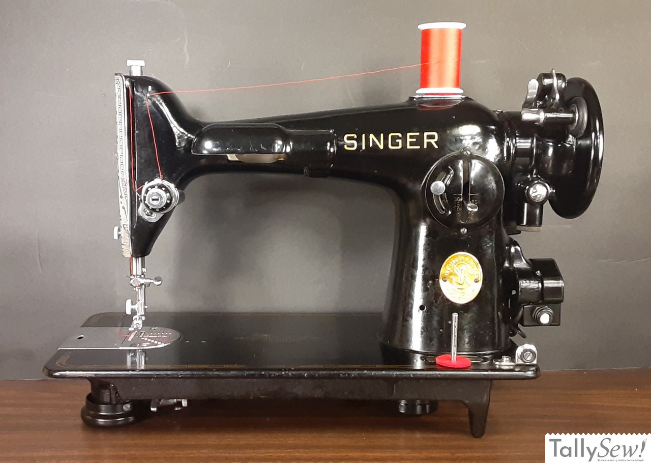 Front view of a vintage Singer 201-2 sewing machine, showing the integrated lamp, stitch length lever, and classic gold decals.