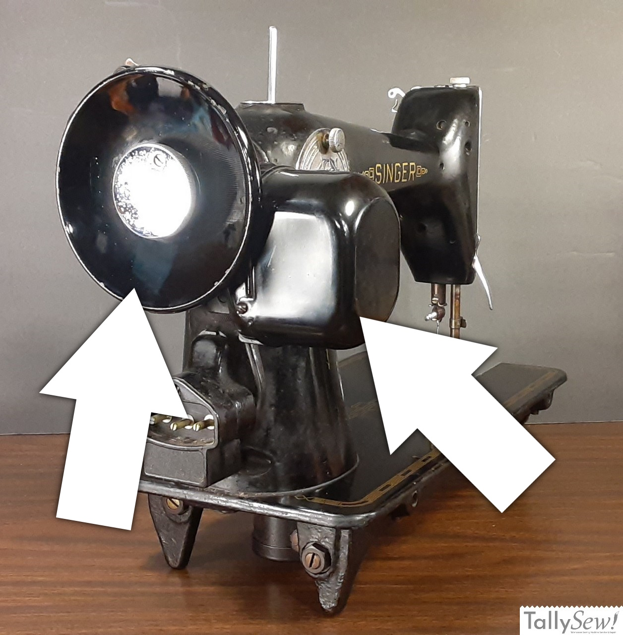 A view of a Singer 201-2 sewing machine with two annotated arrows. The arrow on the left identifies the solid, non-spoked handwheel, while the arrow on the right points to the distinct potted motor.